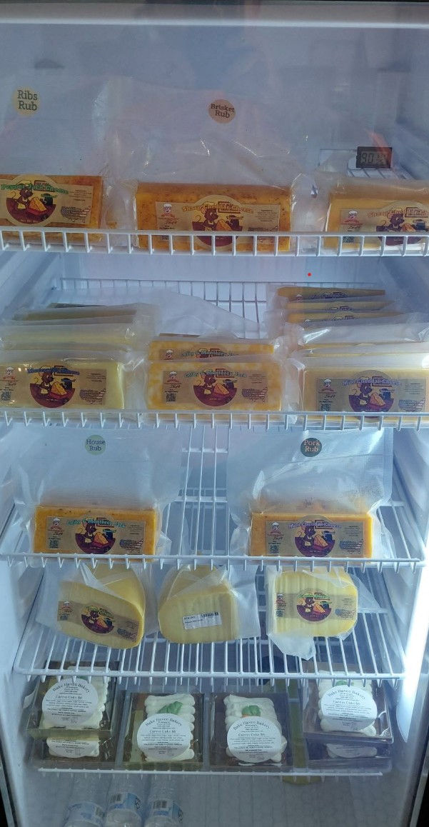 The Fat Piggies cheese case — shelves stocked with smoked cheese blocks and wedges